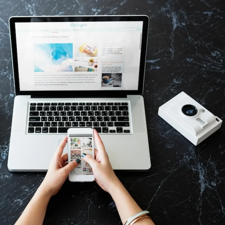 Ręka używa telefonu i laptopa na marmurowym stole