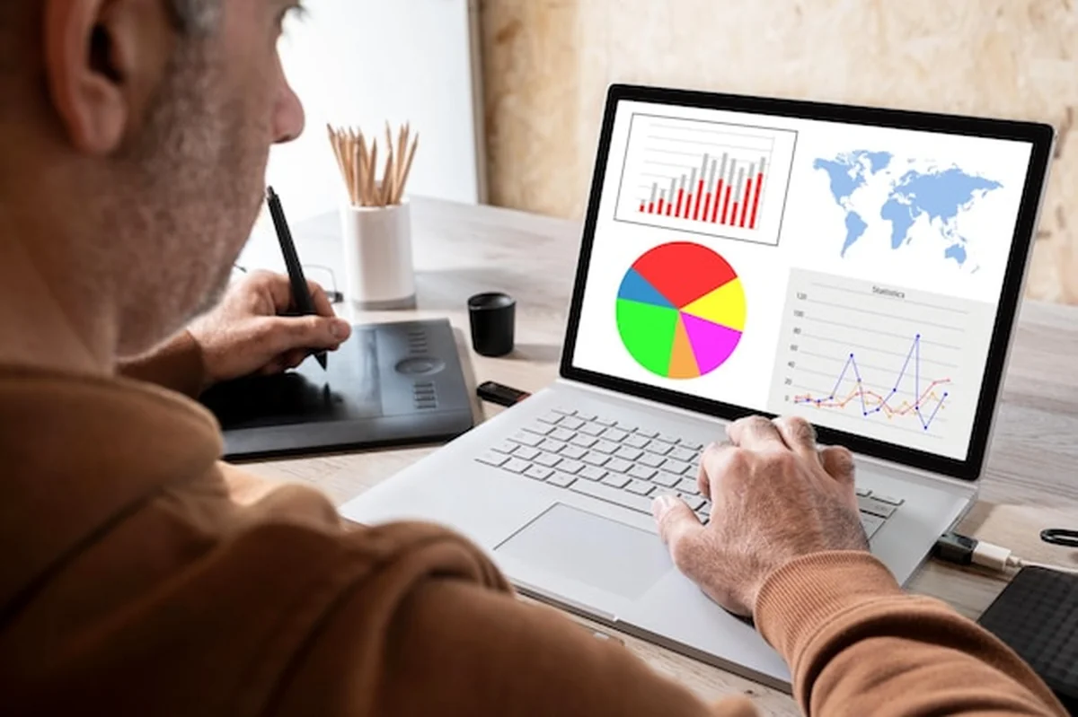 Biznesmen analizujący statystyki na laptopie z wykresami finansowymi online