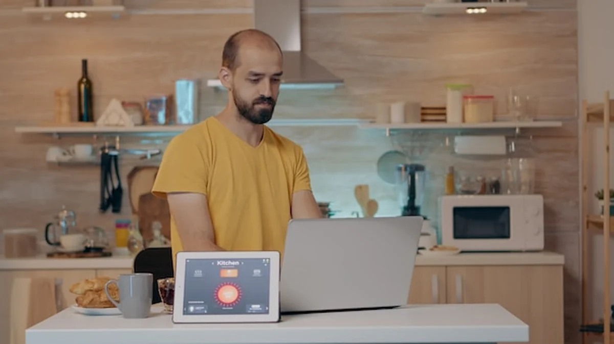 Zdalna osoba pracująca w nowoczesnym domu, wydająca polecenia głosowe do tabletu z aplikacją inteligentnego domu