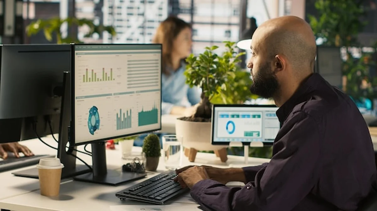 Pracownik edytuje dokumenty na komputerze stacjonarnym przy biurku w biurze