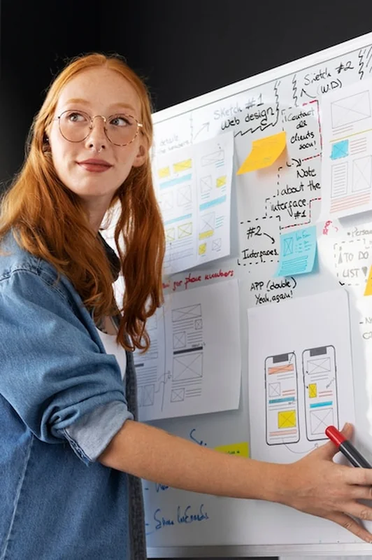 Kobieta projektantka stron internetowych w biurze z papierami i notatkami