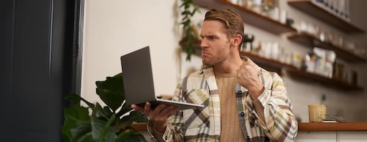 Wściekły mężczyzna z laptopem w ręku w kawiarni